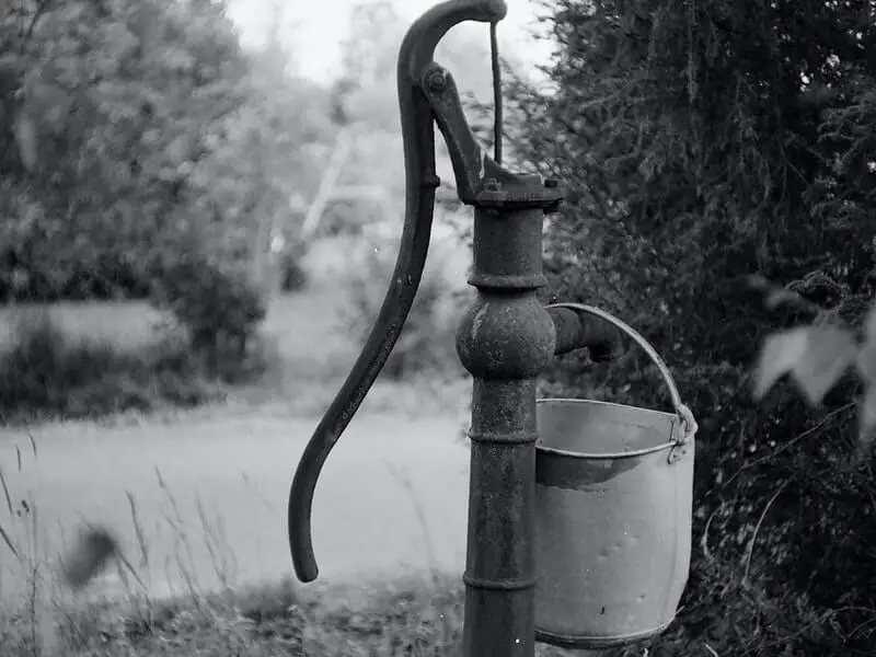 an old water pump pouring water into a bucket